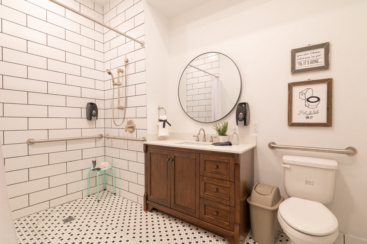 Modern minimalist bathroom with a tiled shower and wooden vanity.