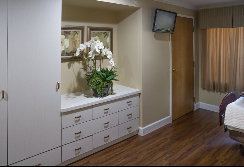 A hallway with a set of drawers and decorative accents, including orchids and paintings.