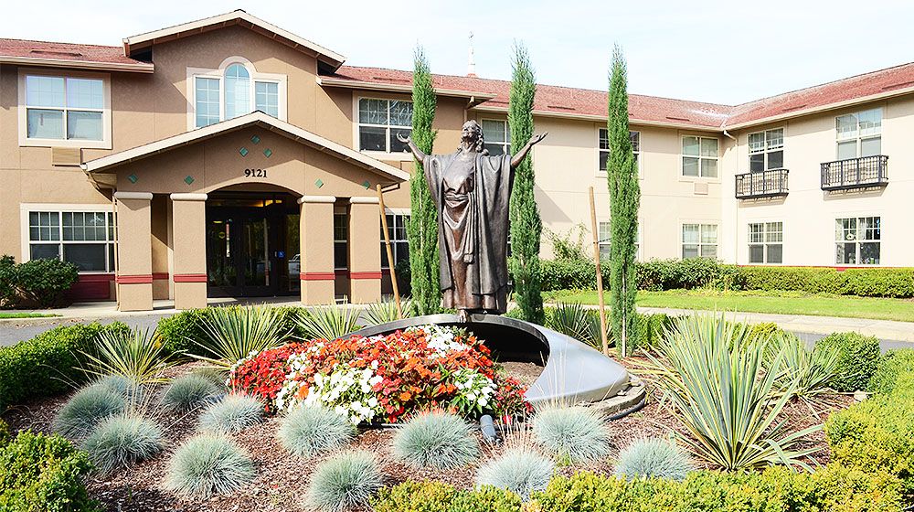 A statue surrounded by a beautifully landscaped garden in front of a building.