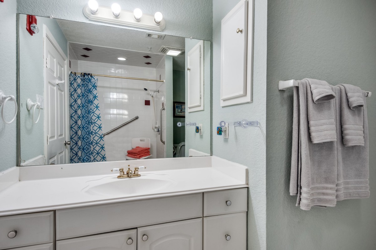 A modern bathroom with a sink, mirror, and shower area.