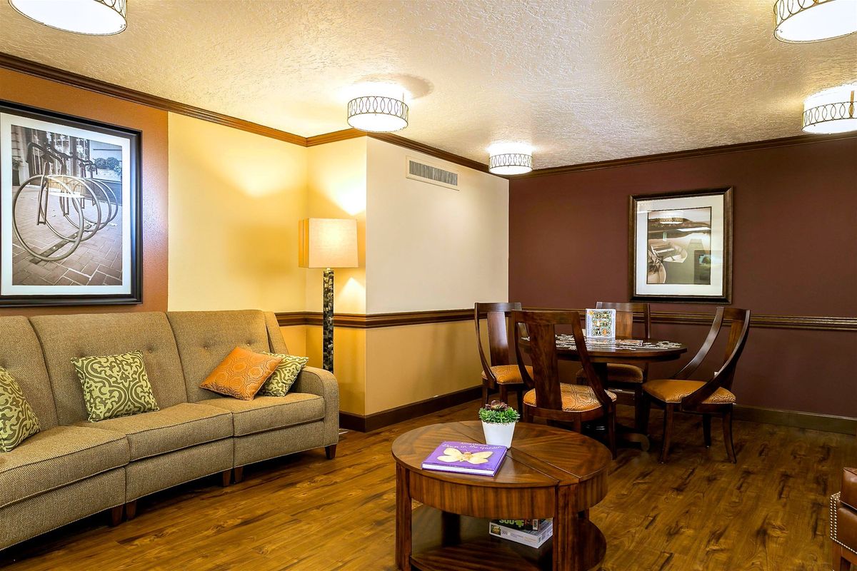 A cozy living room with modern furniture, featuring a sofa, dining table, and coffee table on a wooden floor.