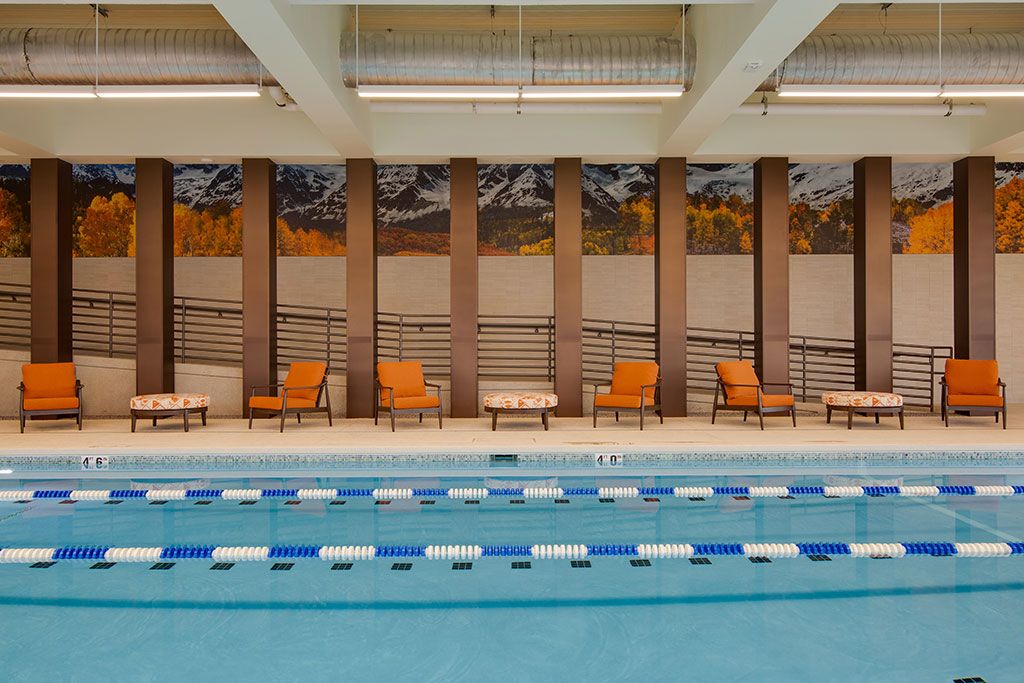 A serene indoor swimming pool with lounge chairs lined up along the side.
