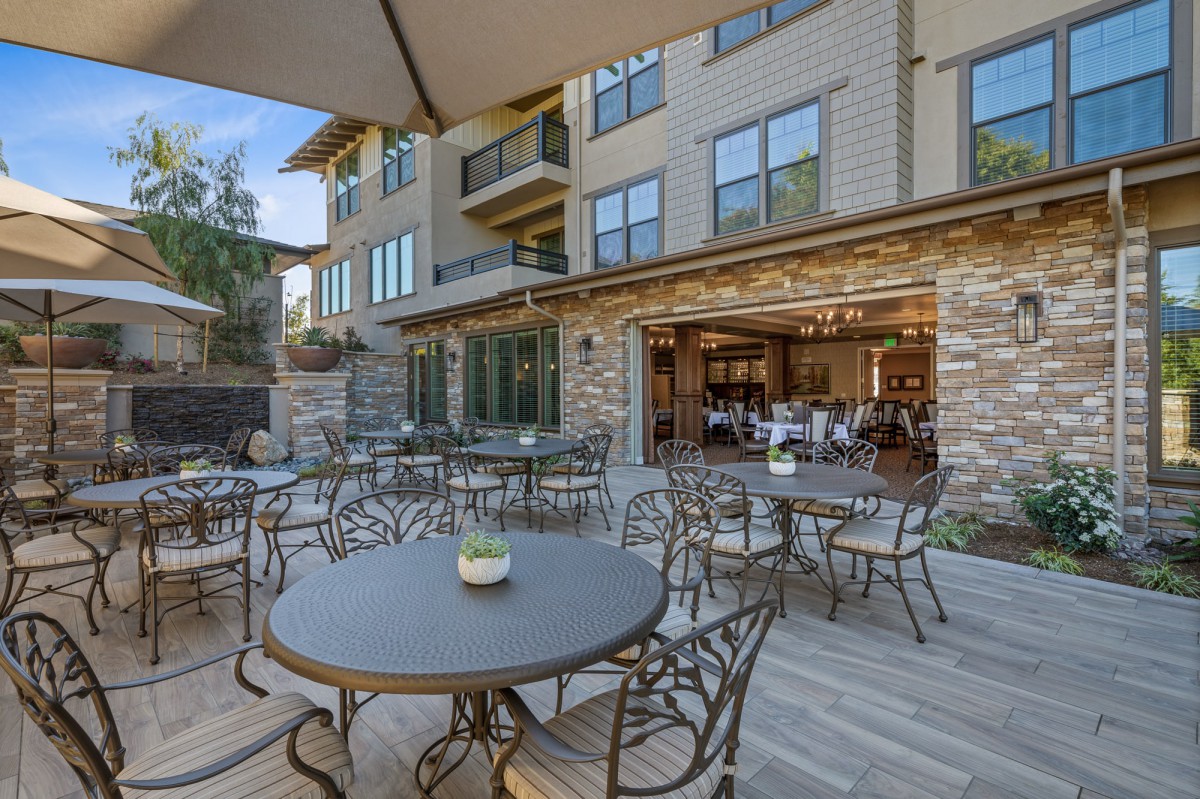 An outdoor patio area with tables and chairs in front of a building, providing a pleasant dining setting.