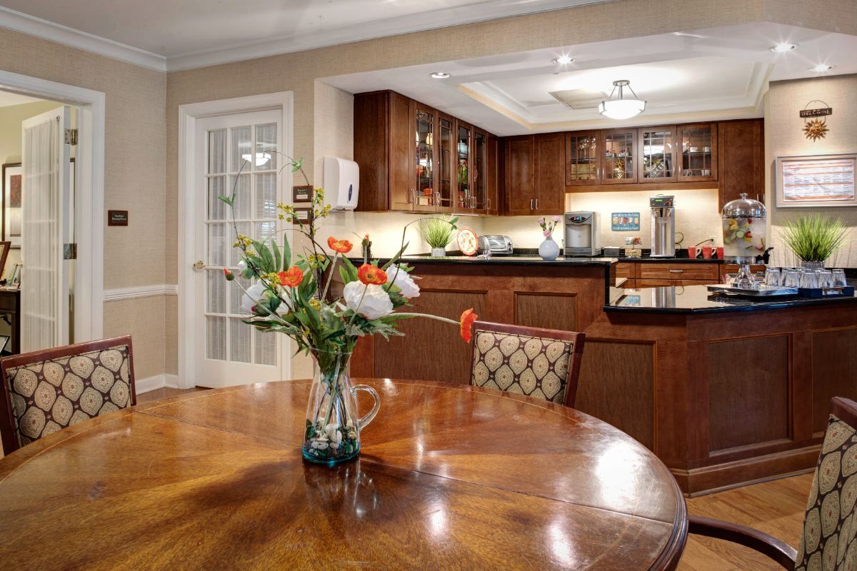 A cozy dining area with a wooden table and a view into a modern kitchen.