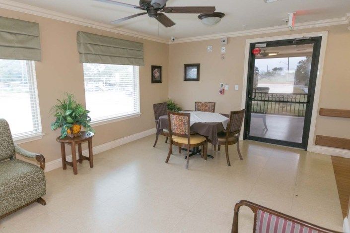A cozy dining area with a table and chairs, featuring a window, plant, and ceiling fan.