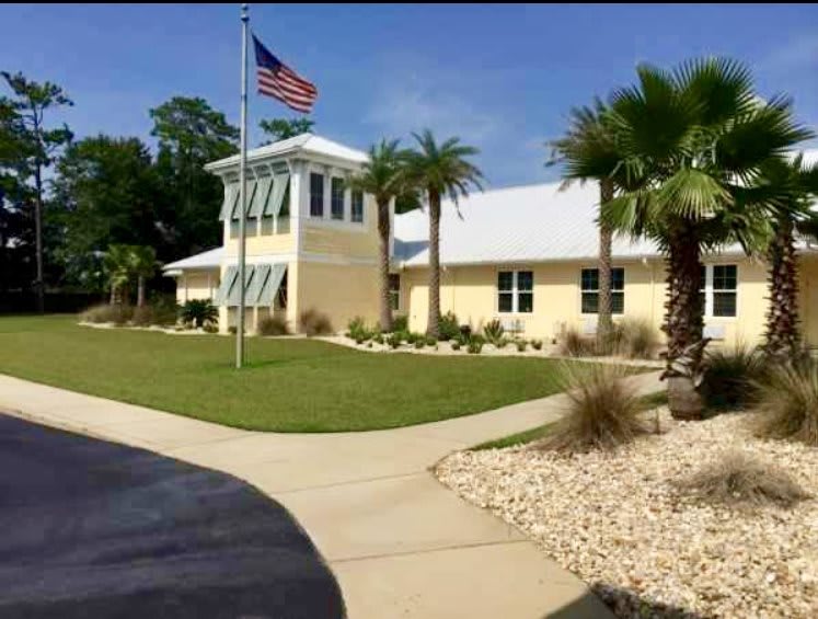A building with an American flag and palm trees, surrounded by well-maintained landscaping on a sunny day.