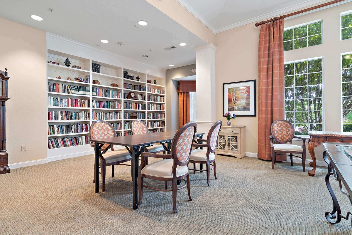 A cozy library room with a table and chairs surrounded by bookshelves.