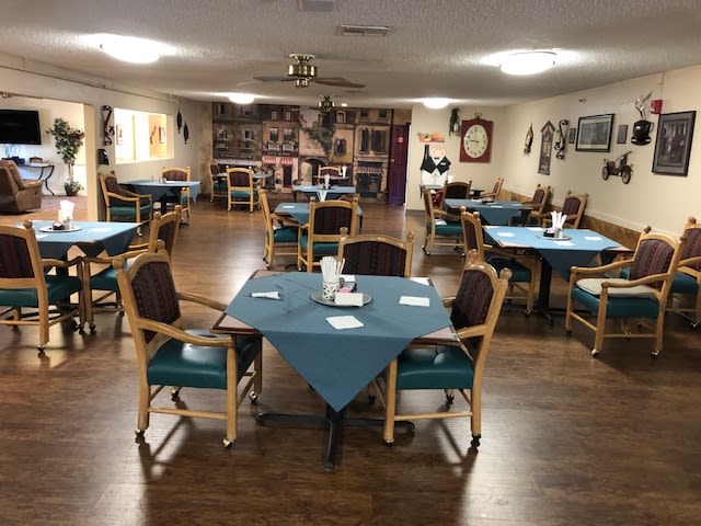 An empty dining room with arranged tables and chairs, decorated in a cozy style.