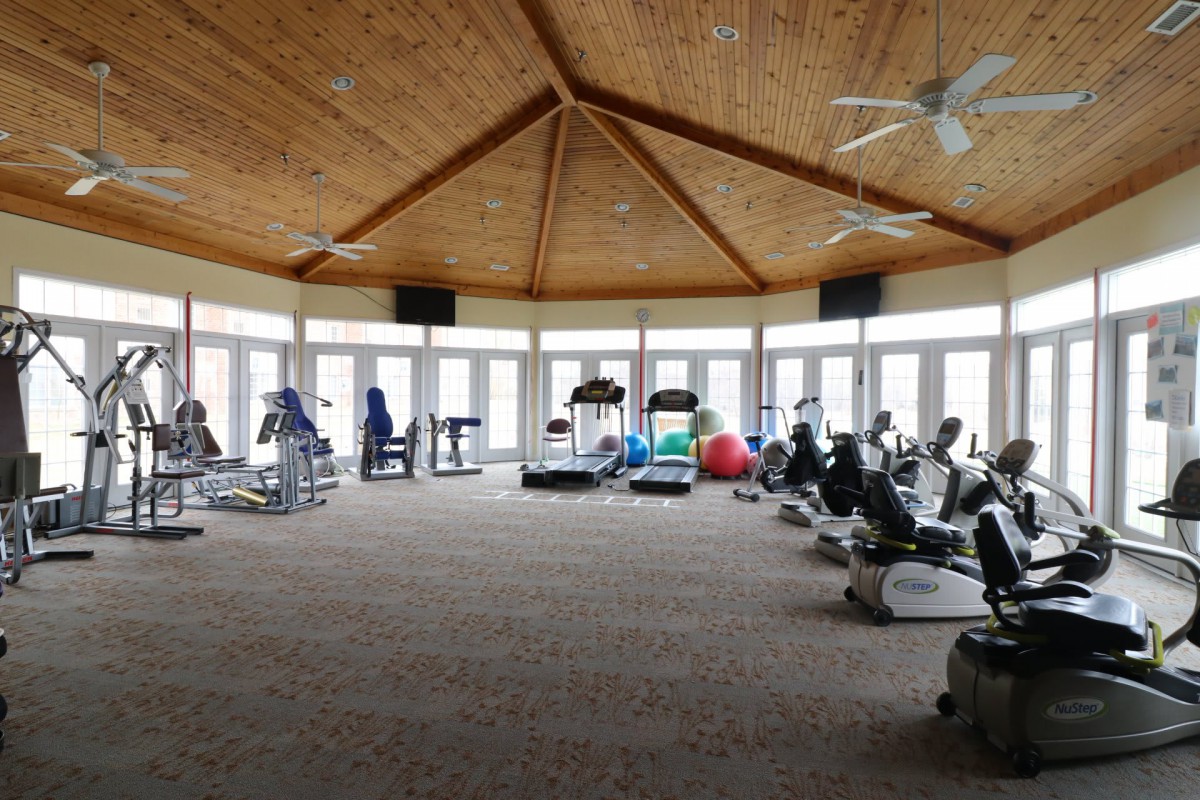 A spacious gym with various exercise equipment and a wooden ceiling.