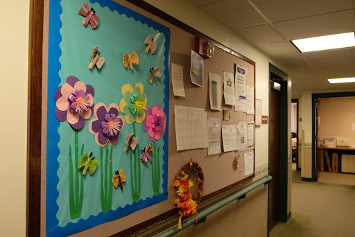 A colorful bulletin board adorned with paper flowers and butterflies, brightening up the hallway.
