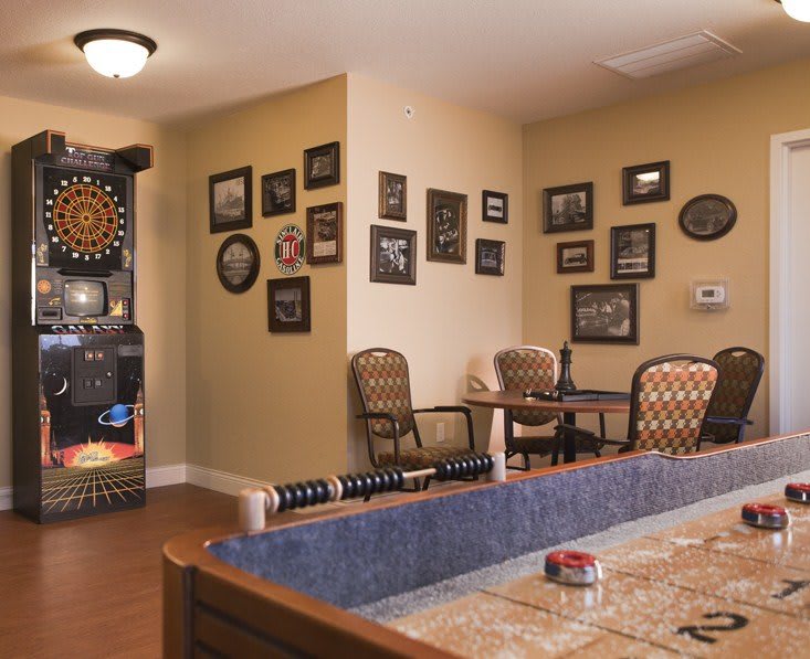 A cozy game room featuring a dartboard, wall art, and comfortable seating arrangements.