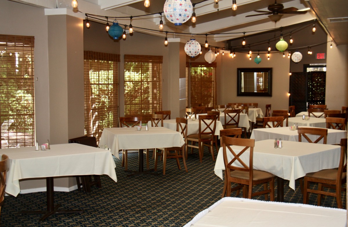An elegantly decorated restaurant dining room with tables and chairs, adorned with decorative lighting.