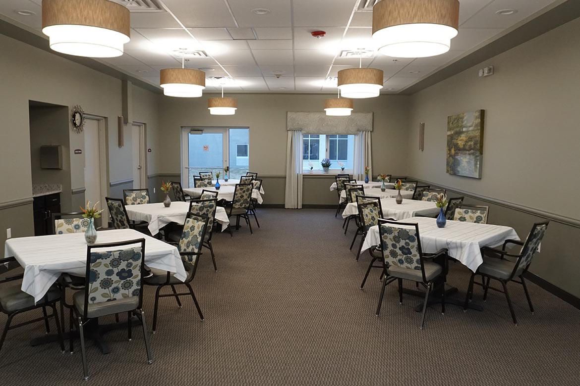 A formal dining room with neatly arranged tables and chairs, featuring elegant lighting and decor.