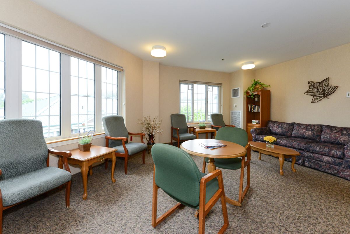 A cozy living room with several chairs, tables, and a sofa arranged near large windows.