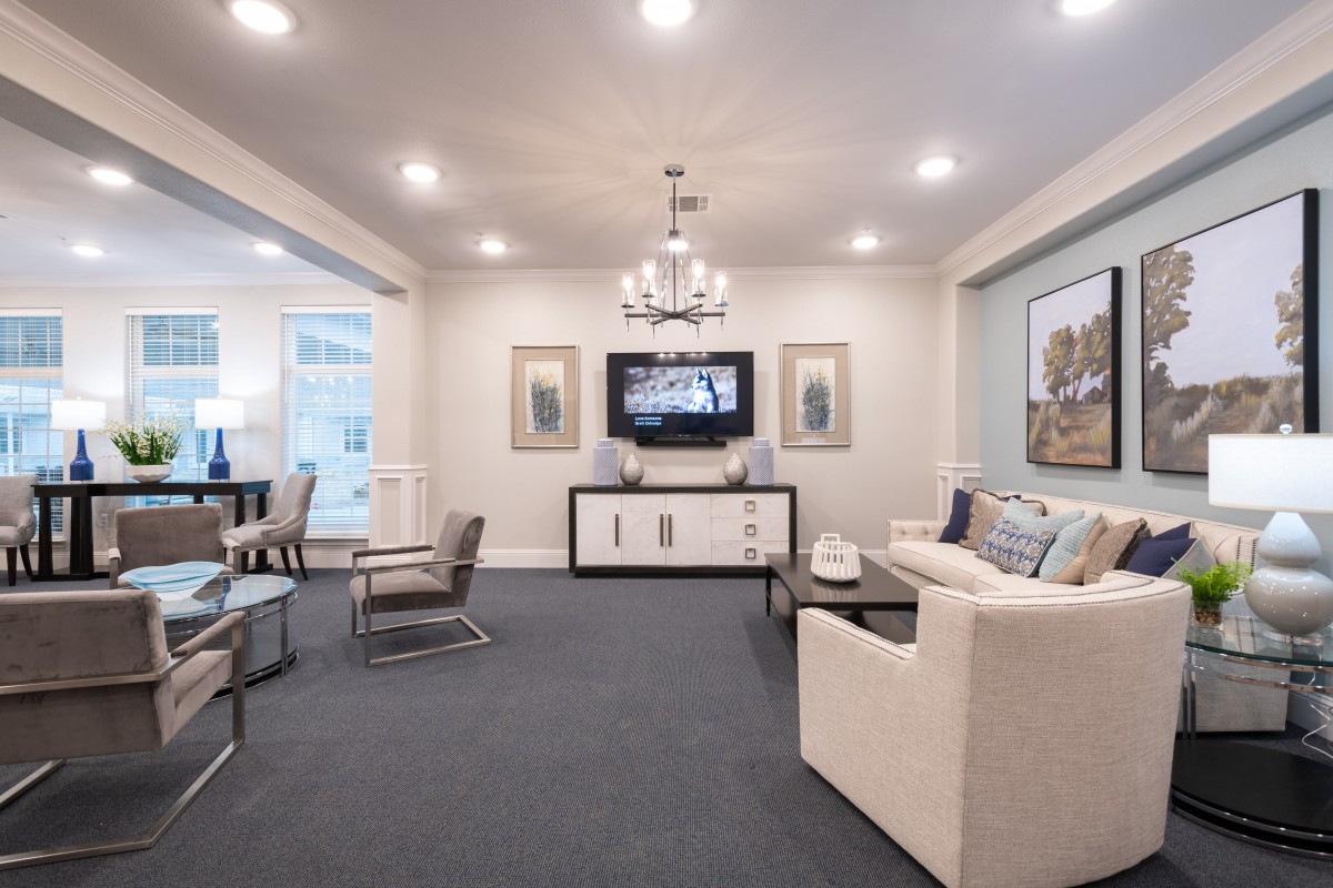 A modern and elegantly decorated living room with a chandelier, comfortable seating, and stylish wall art.