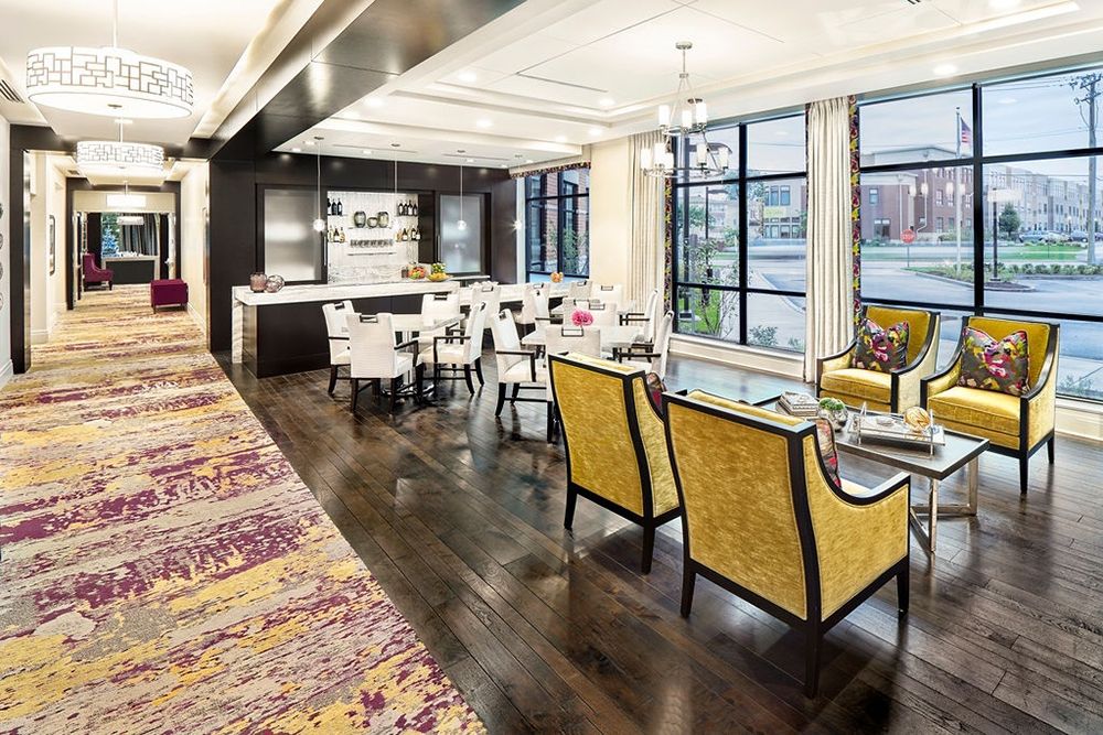 A modern open-concept living and dining area with a kitchen, featuring stylish furniture and large windows that provide ample natural light.