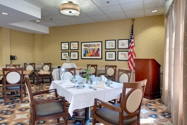 A well-appointed dining area with elegantly set tables, an American flag, and framed artwork on the walls.