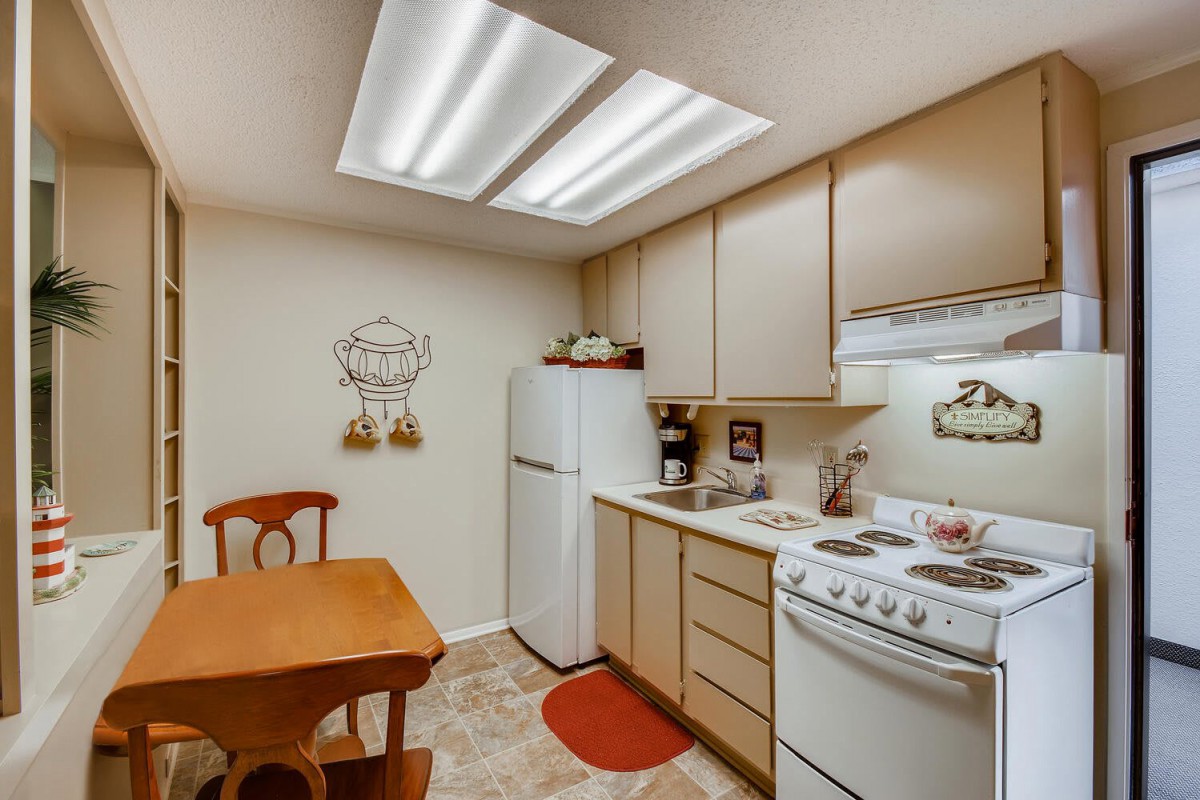 A cozy kitchen with wooden cabinets, a small dining table, and essential appliances.