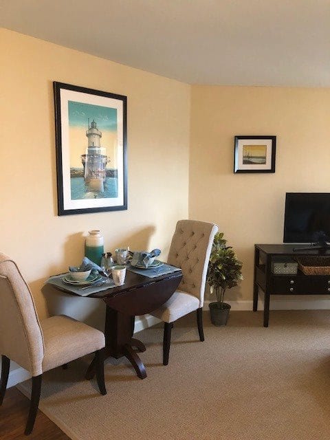 A cozy dining and living space with a small dining table, chairs, and a TV setup.