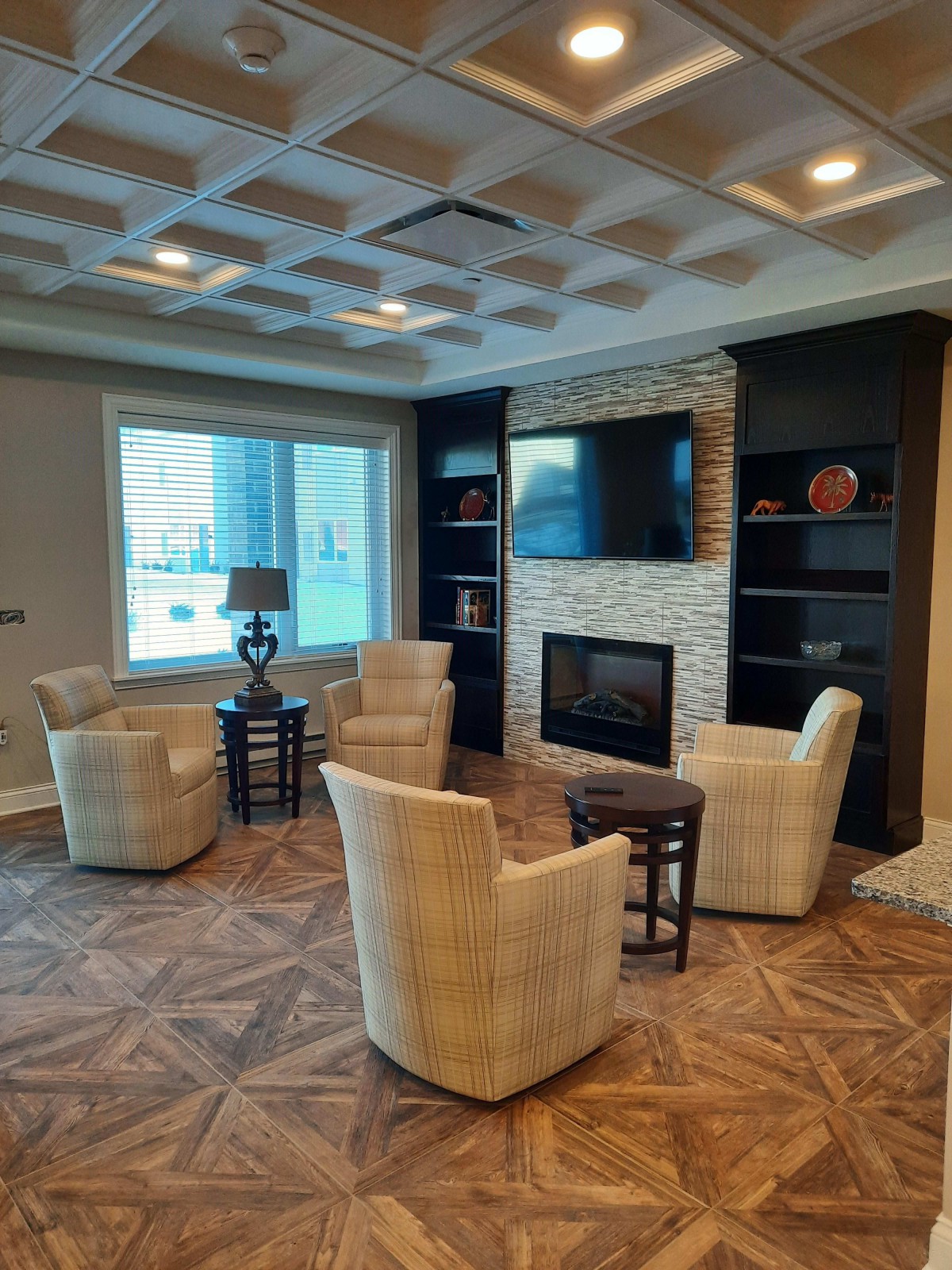 A modern living room with a cozy seating area around a fireplace, featuring bookshelves and elegant furniture.