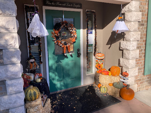 A cozy front porch adorned with festive Halloween decorations, featuring pumpkins and a seasonal wreath.