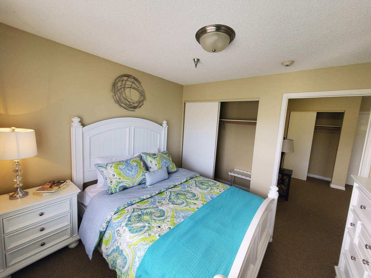 A cozy bedroom with colorful bedding and a spacious closet.