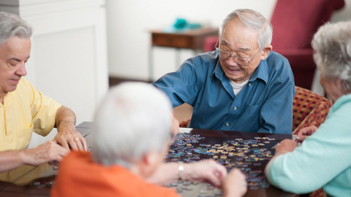A group of seniors collaborating on a puzzle together indoors.