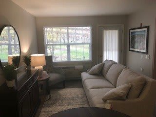 A cozy living room with a sofa, chair, and lamp near a window.