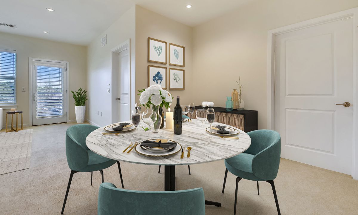 A modern dining room with a round table set for dinner, featuring elegant decor and soft blue chairs.