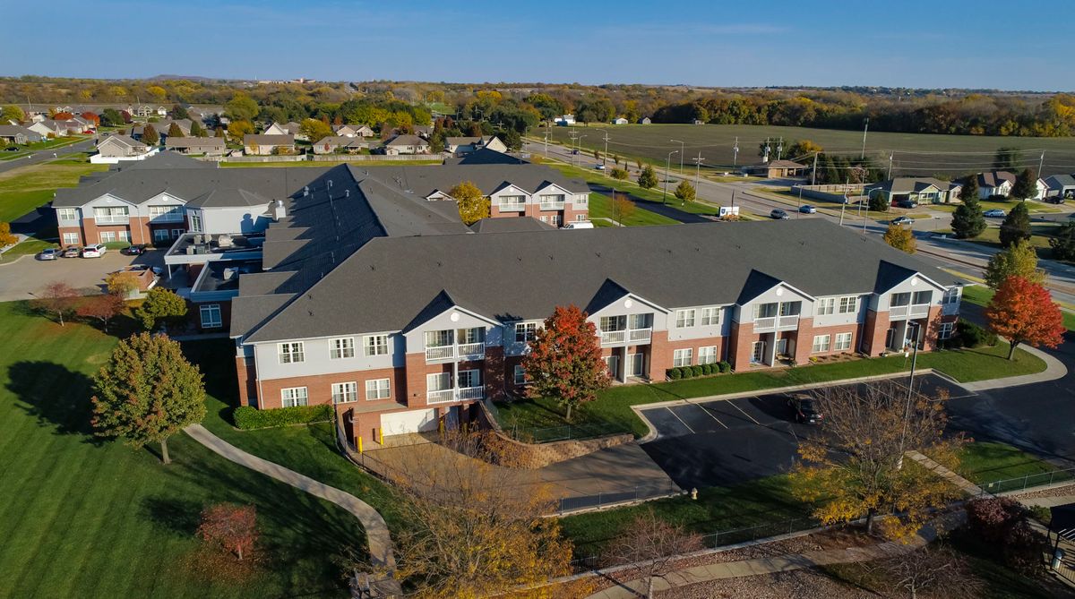 Aerial view of a suburban apartment complex with surrounding greenery and a parking lot.