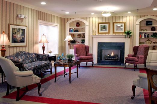 A cozy living room with a fireplace, elegant furniture, and decorative shelving.
