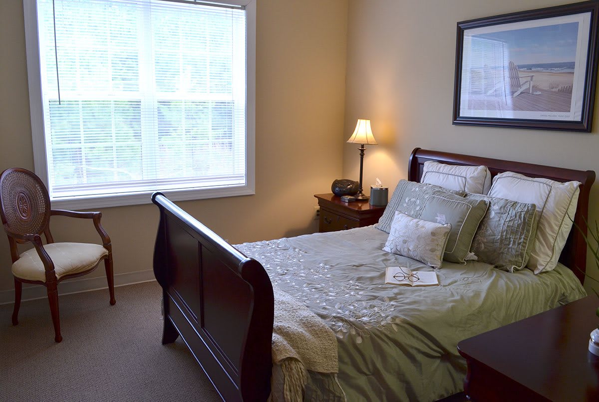 A cozy bedroom with a bed, lamp, and window.