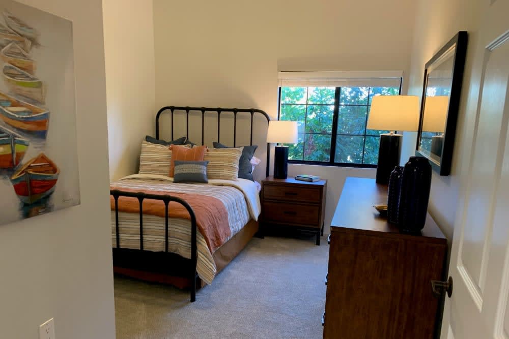 A cozy bedroom with a metal bed frame, colorful bedding, and warm lighting from table lamps.