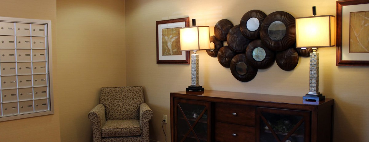 A cozy living room corner featuring a lamp, artwork, and modern wall decor.