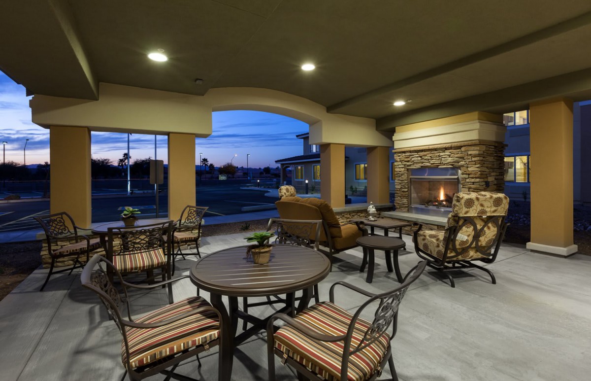 A cozy outdoor patio with a fireplace and comfortable seating at dusk.