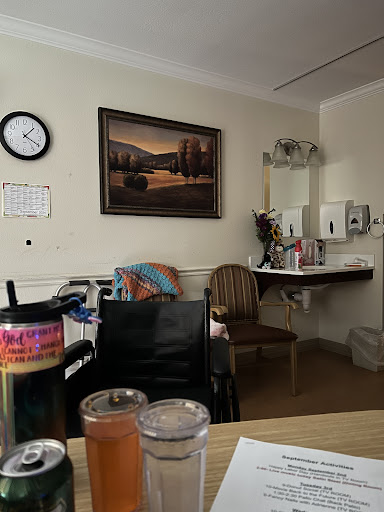 A cozy hospital room featuring a painting, a clock, and various pieces of furniture.