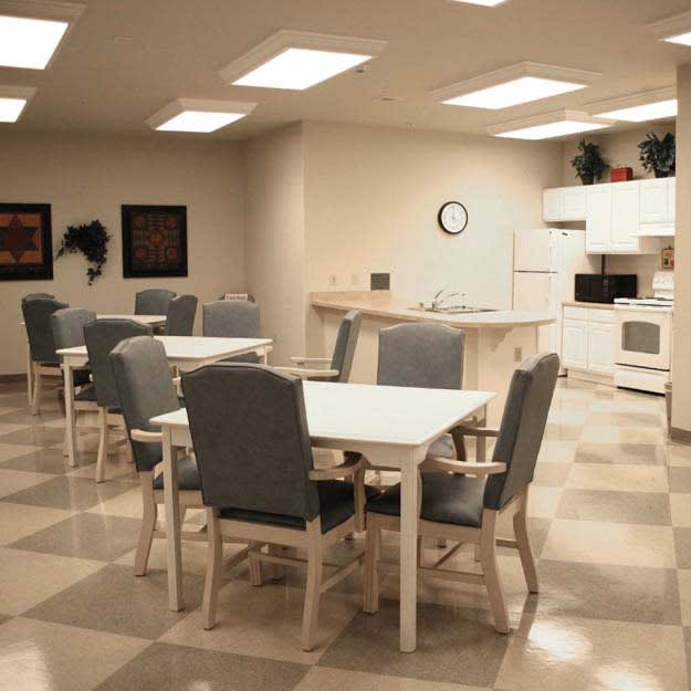 A communal kitchen and dining area with tables, chairs, and appliances.