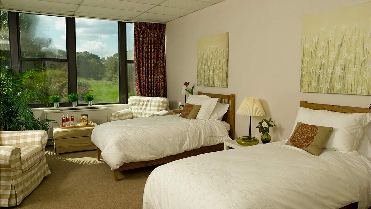 A cozy hotel room with two comfortable beds and a scenic window view.