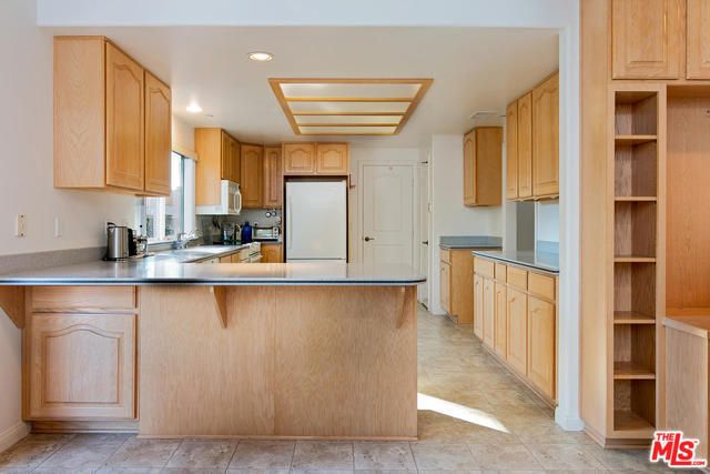 A modern kitchen with wooden cabinets and an island under bright lighting.