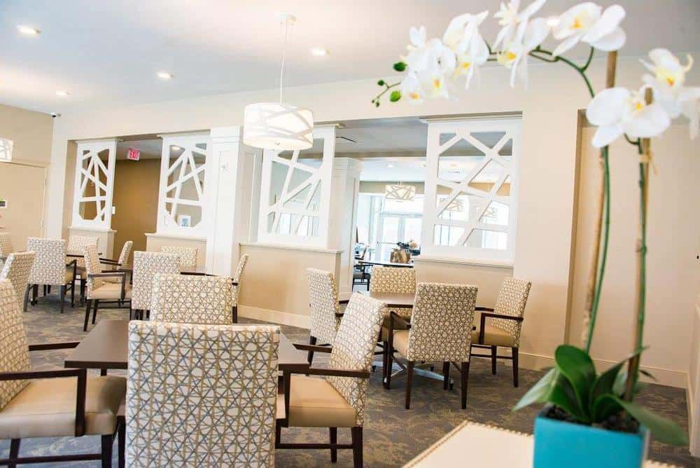 A modern and elegantly designed seating area with patterned chairs and tables under a stylish light fixture.