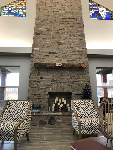 A cozy and modern living room featuring a tall stone fireplace as the focal point.