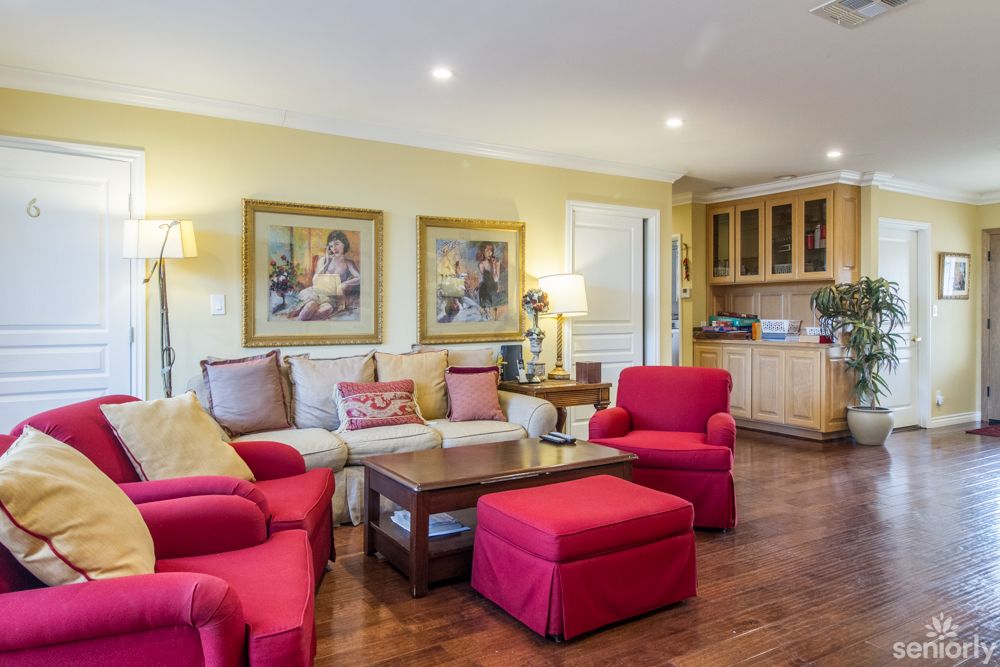 A cozy living room featuring red furniture, artwork, and warm lighting.
