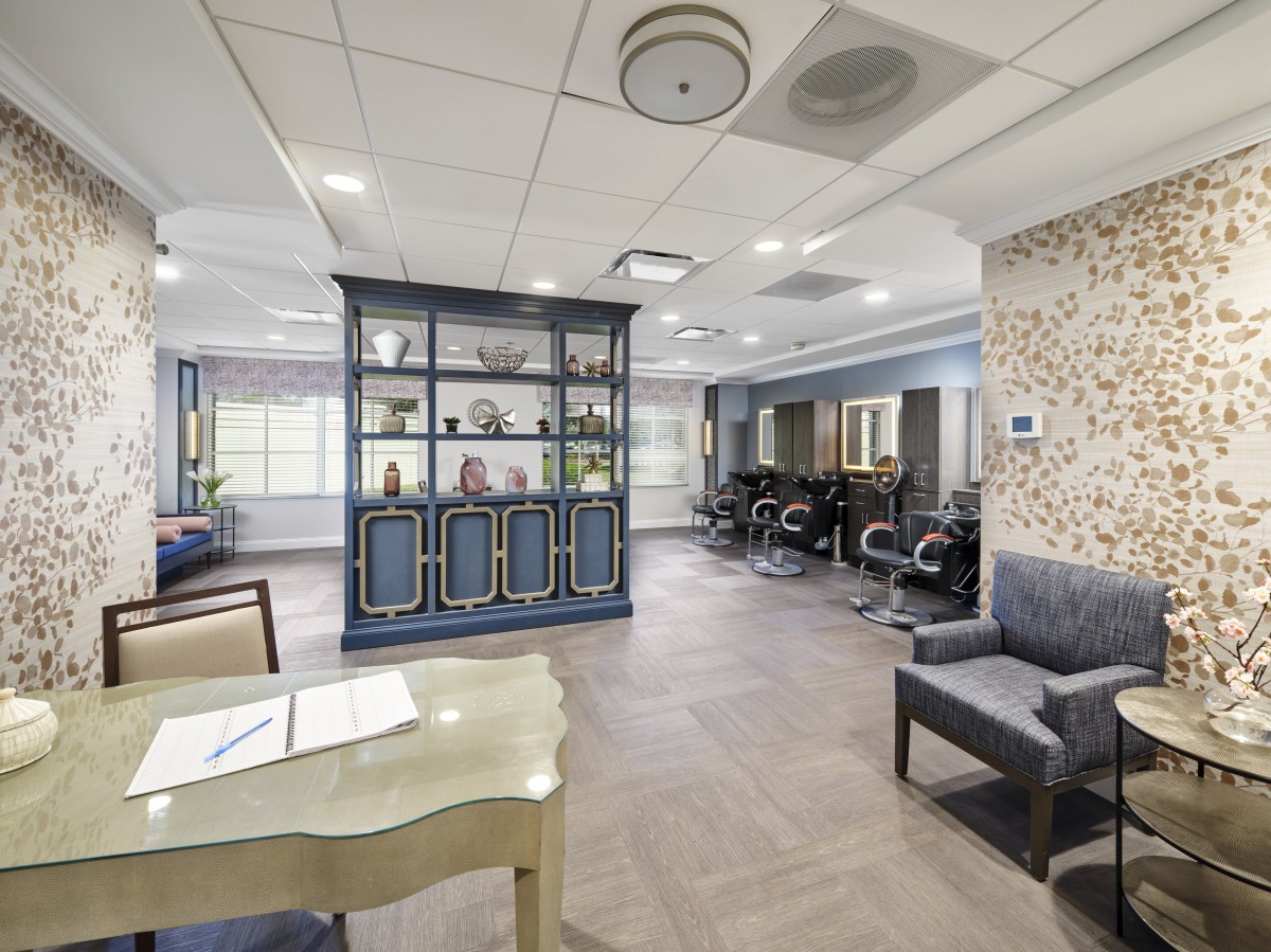A modern interior space featuring a lobby with seating, a reception desk, and exercise equipment.