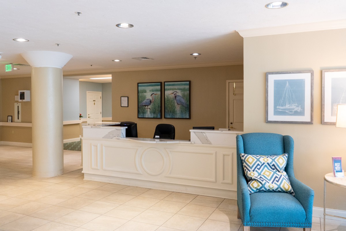A reception area featuring a desk, chairs, and wall art in a well-lit office lobby.