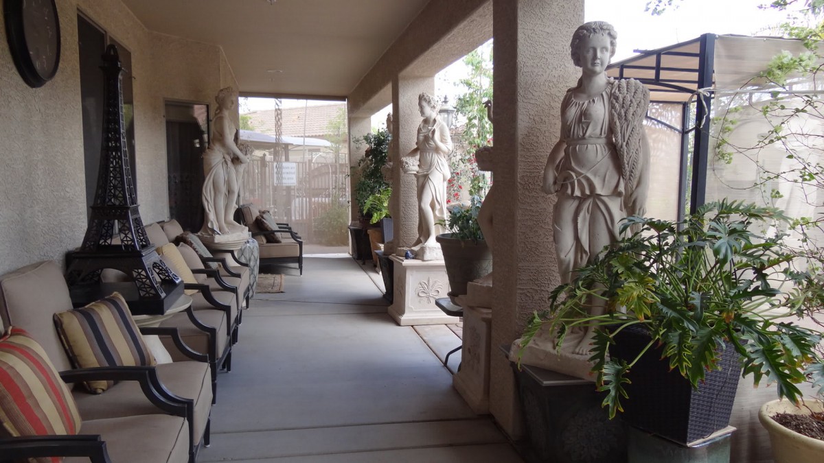 A corridor adorned with classical sculptures and indoor plants, featuring comfortable seating.