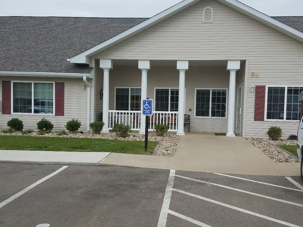 A single-story building with a front porch, columns, and an accessible parking space in front.