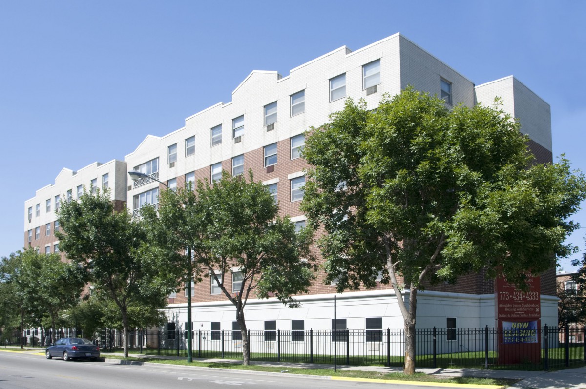 A multi-story residential building with trees lining the street in an urban setting.