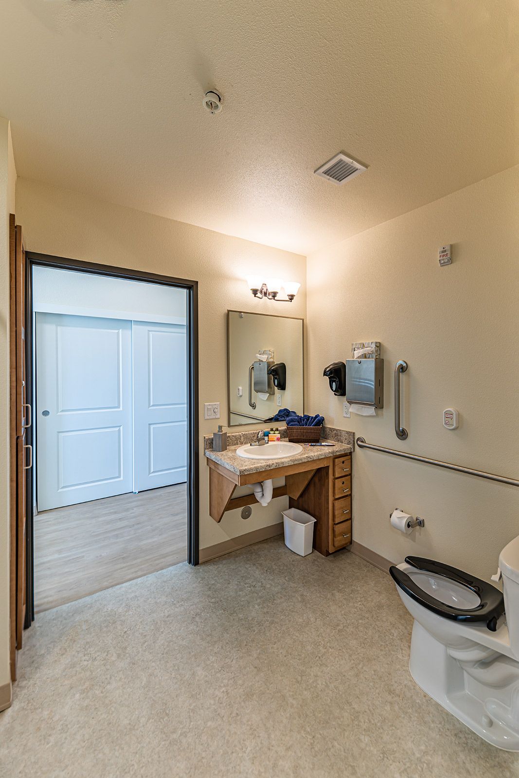 A modern, accessible bathroom with a sink, toilet, and grab bars.