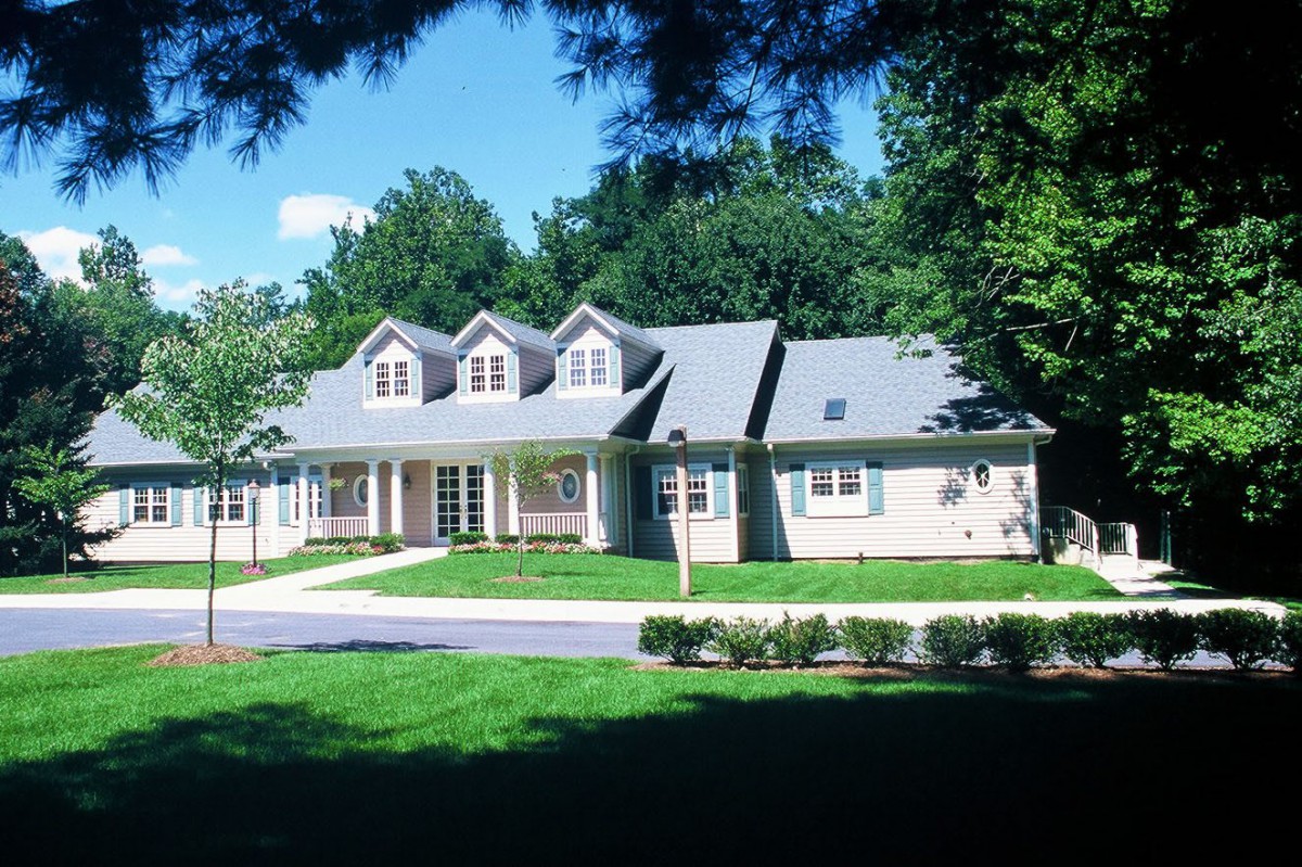 A suburban residential house surrounded by a manicured lawn and trees.