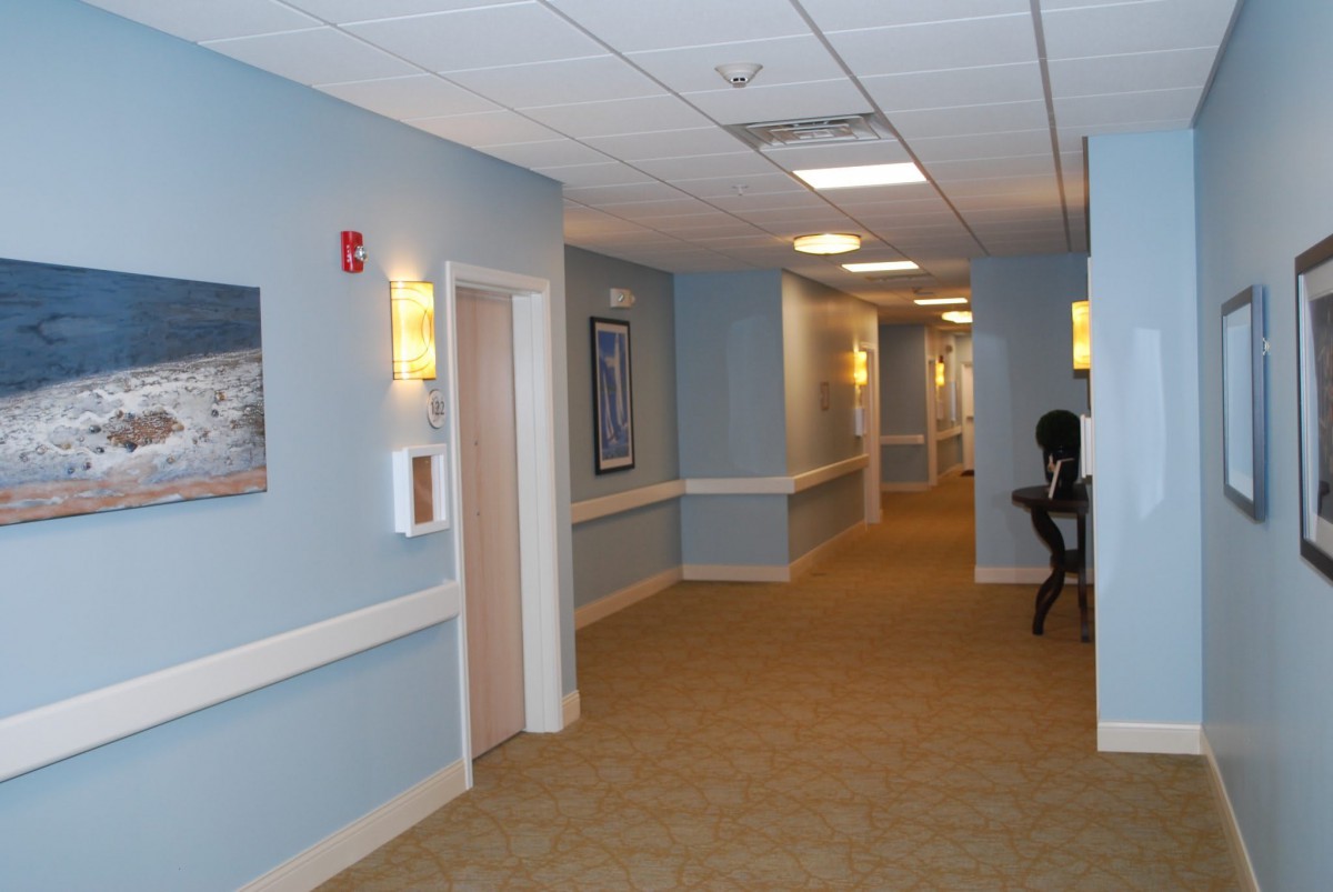 A carpeted hallway with blue walls and framed pictures.